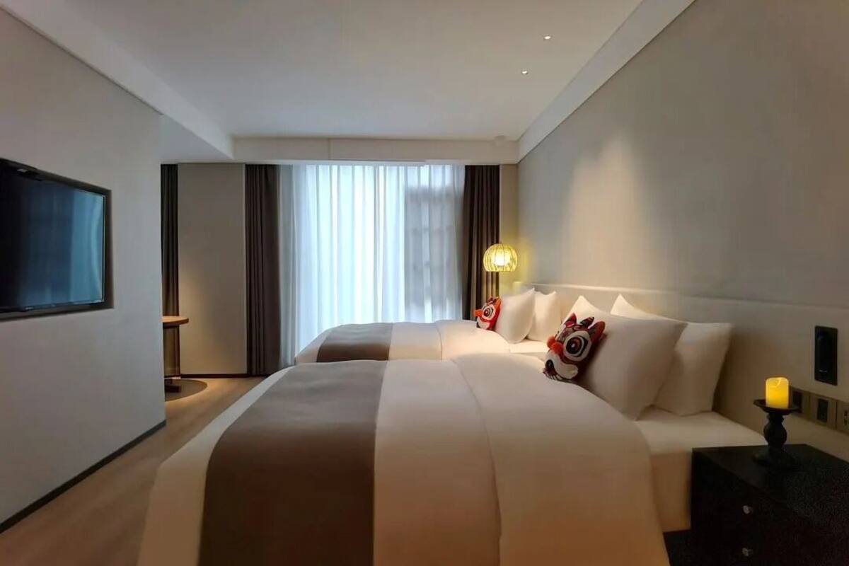 A hotel room with a large bed, a flat-screen TV, a bedside table, and a lamp.
