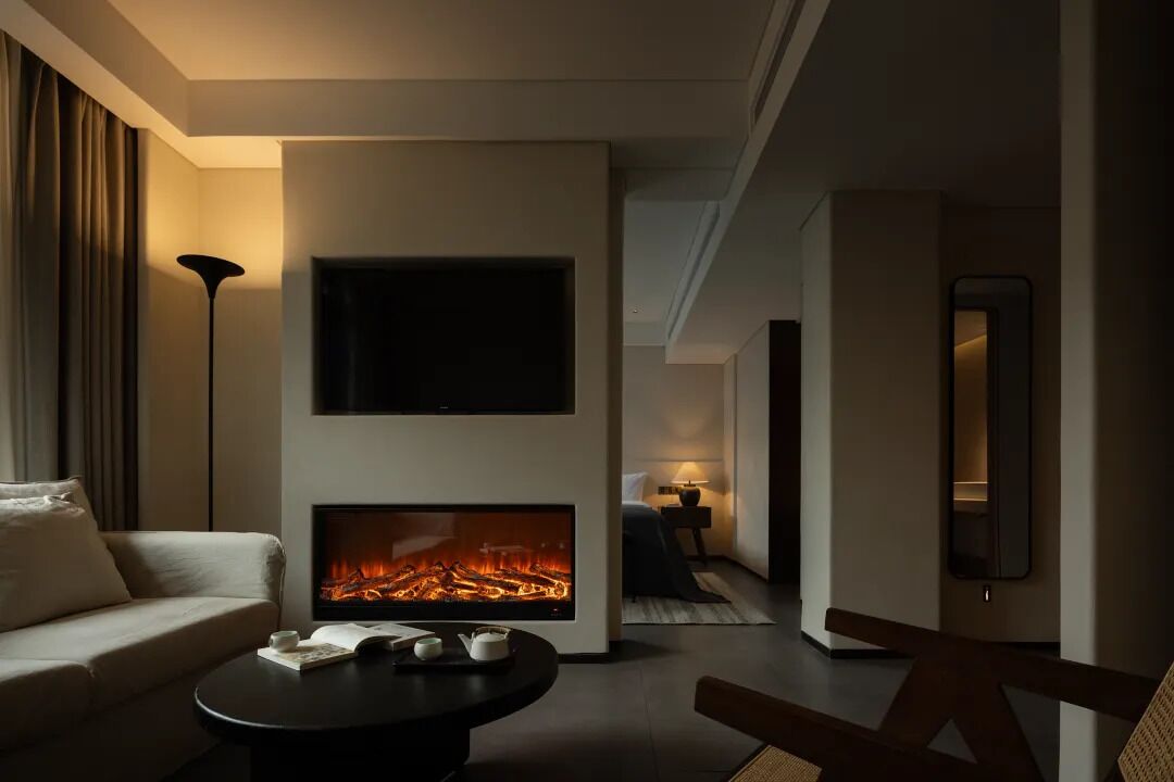 A modern living room with a fireplace, a sofa, a coffee table, and a TV mounted on the wall.