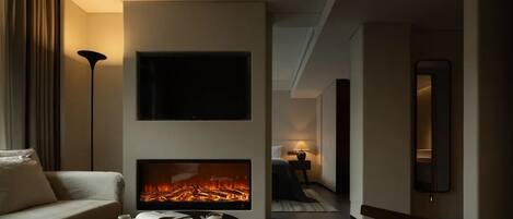 A modern living room with a fireplace, a sofa, a coffee table, and a TV mounted on the wall.