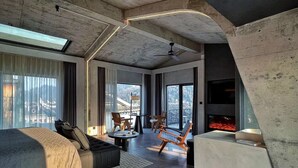 A modern hotel room with a large bed, seating area, and a fireplace. - Phoenix Hall House Hotel (Xiangxi)