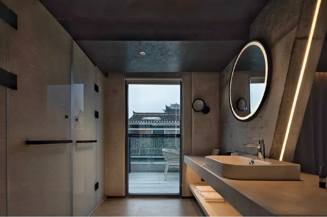 Un baño moderno con un lavamanos grande, un espejo y vistas a la arquitectura tradicional.