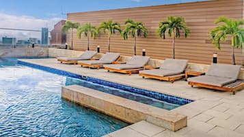 A rooftop pool area with lounge chairs and palm trees.