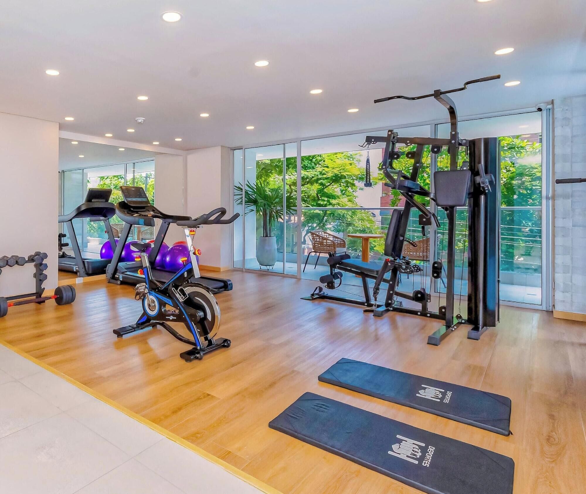 A gym with cardio machines, free weights, and exercise mats.