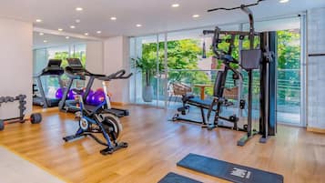 Une salle de sport équipée de machines de cardio, de poids libres et de tapis de sol pour les exercices.