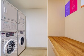 A laundry area with stacked washing machines and a wooden counter.