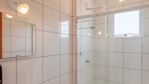 A modern bathroom with white tiles, a glass shower enclosure, a window, and a mirror. - Apt w/ BBQ Near the Waterfront Ubatuba-sp Cdv042 (Ubatuba)