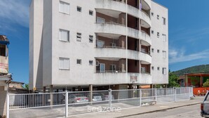 A multi-story building with balconies, a parking area, and a fenced entrance. - Apt w/ BBQ Near the Waterfront Ubatuba-sp Cdv042 (Ubatuba)