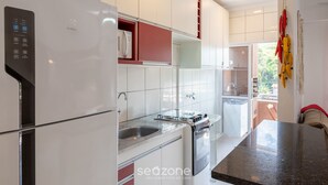 A modern kitchen with white cabinets, a built-in oven, and a stainless steel sink. - Apt w/ BBQ Near the Waterfront Ubatuba-sp Cdv042 (Ubatuba)