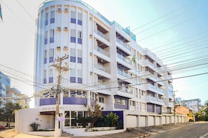 Un edificio de varios pisos con balcones, una entrada con reja y un cielo despejado.