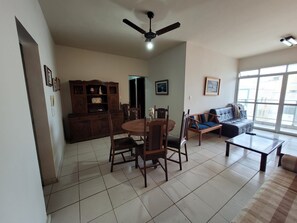 A living room with a dining table, chairs, a sofa, and a ceiling fan.