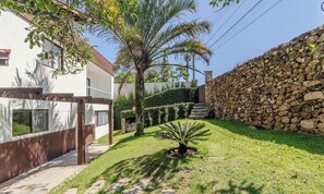 A residential property with a stone wall, a palm tree, and a well-maintained lawn. - 4BR House Pool & BBQ 500m From Beach Che0401 (Bombinhas)