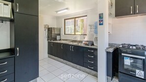 Une cuisine moderne avec des meubles de couleur noire, un four à micro-ondes, une cuisinière et une fenêtre qui laisse entrer la lumière naturelle.