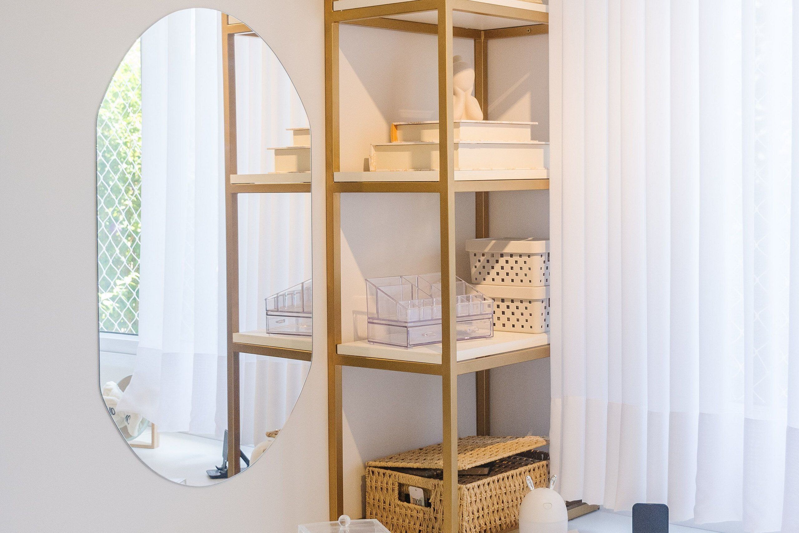 Een kamer met een spiegelwand, een houten wandplank met opbergmanden, en een witte sculptuur.