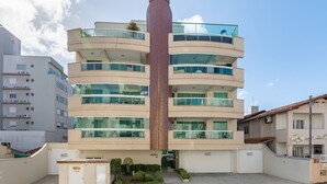 Un edificio de varios pisos con un pilar central rojo, balcones y una entrada con portones.