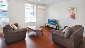Uma sala de estar com dois sofás, uma mesa de centro e uma televisão.