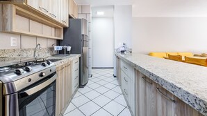 A modern kitchen with wooden cabinets, a stainless steel stove, and a granite countertop.
