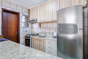 Une cuisine moderne dotée de plans de travail en granit, d’appareils électroménagers en acier inoxydable et de meubles en bois.