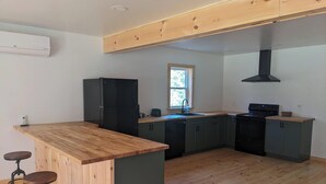 A modern kitchen with wooden countertops, a black refrigerator, and a built-in oven. - The Cabins at Timber Ridge - #3 - Brand new cabins nestled in the woods of NH (Tamworth)