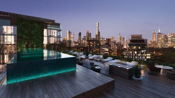 Un área de piscina en la azotea con vista al horizonte de la ciudad, mobiliario de descanso y una terraza de madera.