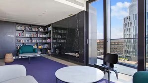 Una biblioteca moderna con estanterías, asientos y un amplio ventanal con vistas a la ciudad.
