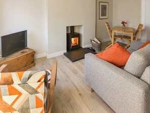A cozy living room with a fireplace, a television, a sofa, and a dining table.