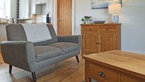 Un salon moderne avec un canapé gris, un meuble en bois et un tableau représentant un paysage marin.