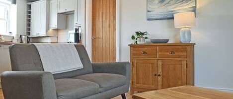 A modern living room with a grey sofa, wooden cabinet, and a painting of a seascape.