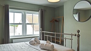 Une chambre à coucher avec un lit, une fenêtre, un miroir et un radiateur.