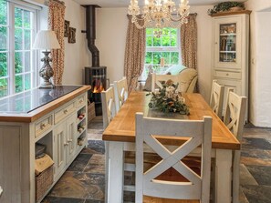 A dining area with a wooden table, white chairs, a fireplace, and a chandelier.