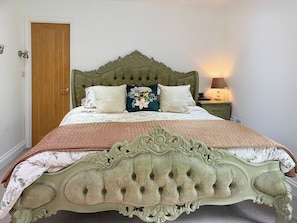 A bed with a tufted headboard, a bedside table with a lamp, and a door to the left.