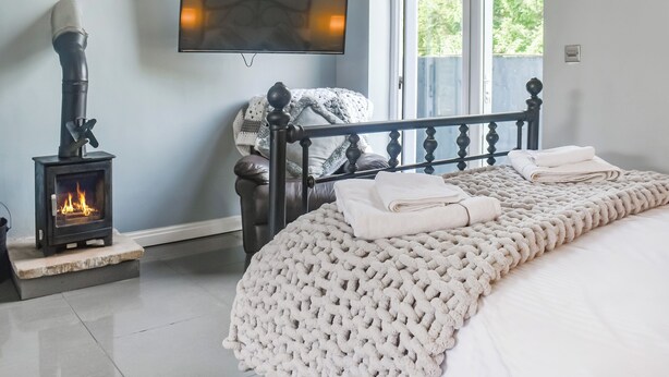 A bedroom with a bed, a TV mounted on the wall, a fireplace, and a window. - 1 bedroom accommodation in Clitheroe (Clitheroe)