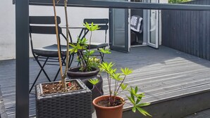 A balcony with potted plants, a chair, and a sliding glass door leading to a room. - 1 bedroom accommodation in Clitheroe (Clitheroe)