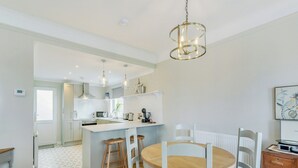 A modern kitchen with white cabinetry, a central island, and pendant lighting. - 4 bedroom accommodation in Balintore (Balintore)