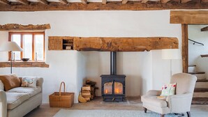 Una stanza accogliente con soffitto in legno, un camino, un divano, una poltrona e una finestra.