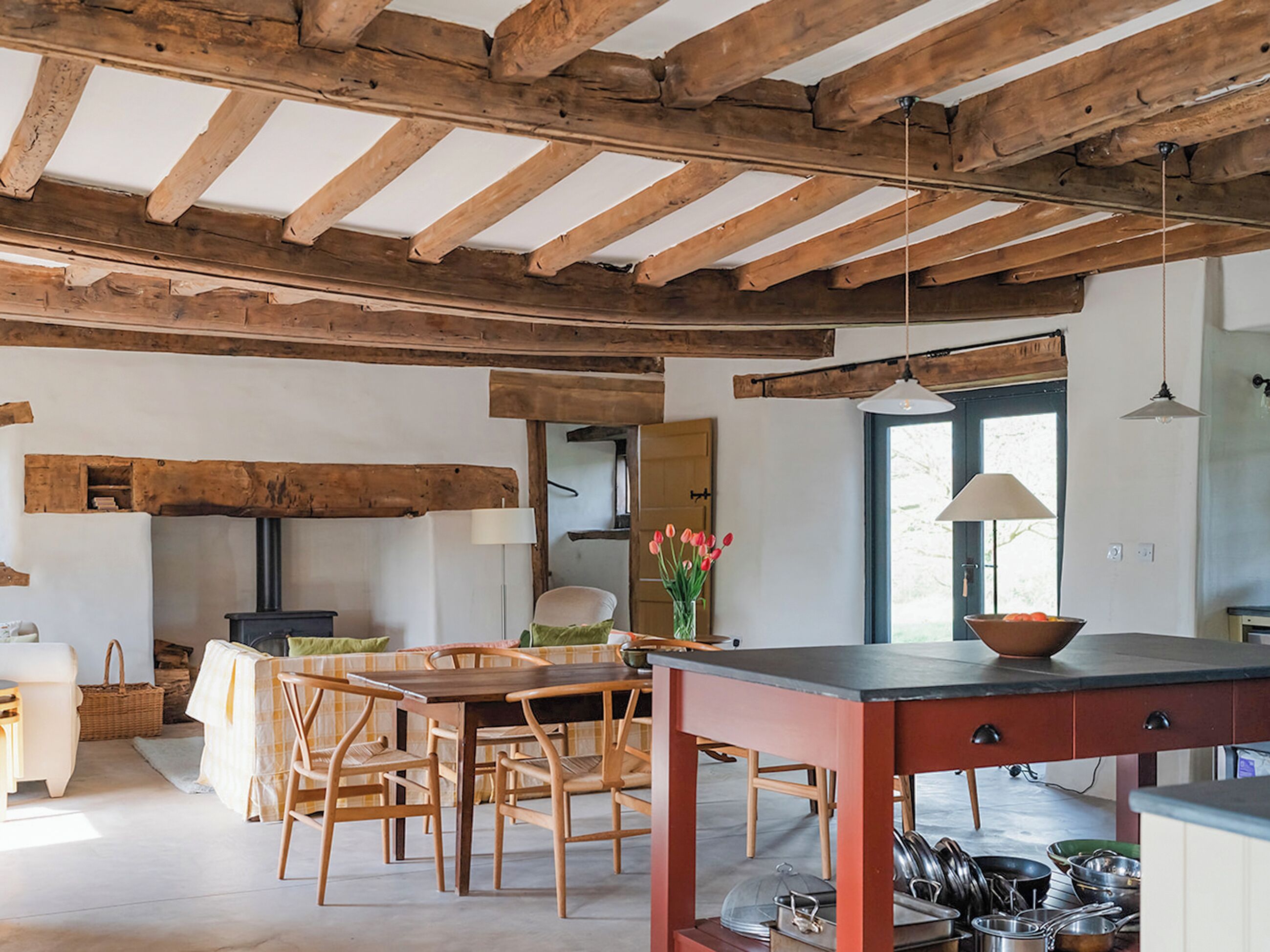 Una cocina rústica con vigas de madera, un comedor con sillas de madera, una mesa y una estufa.