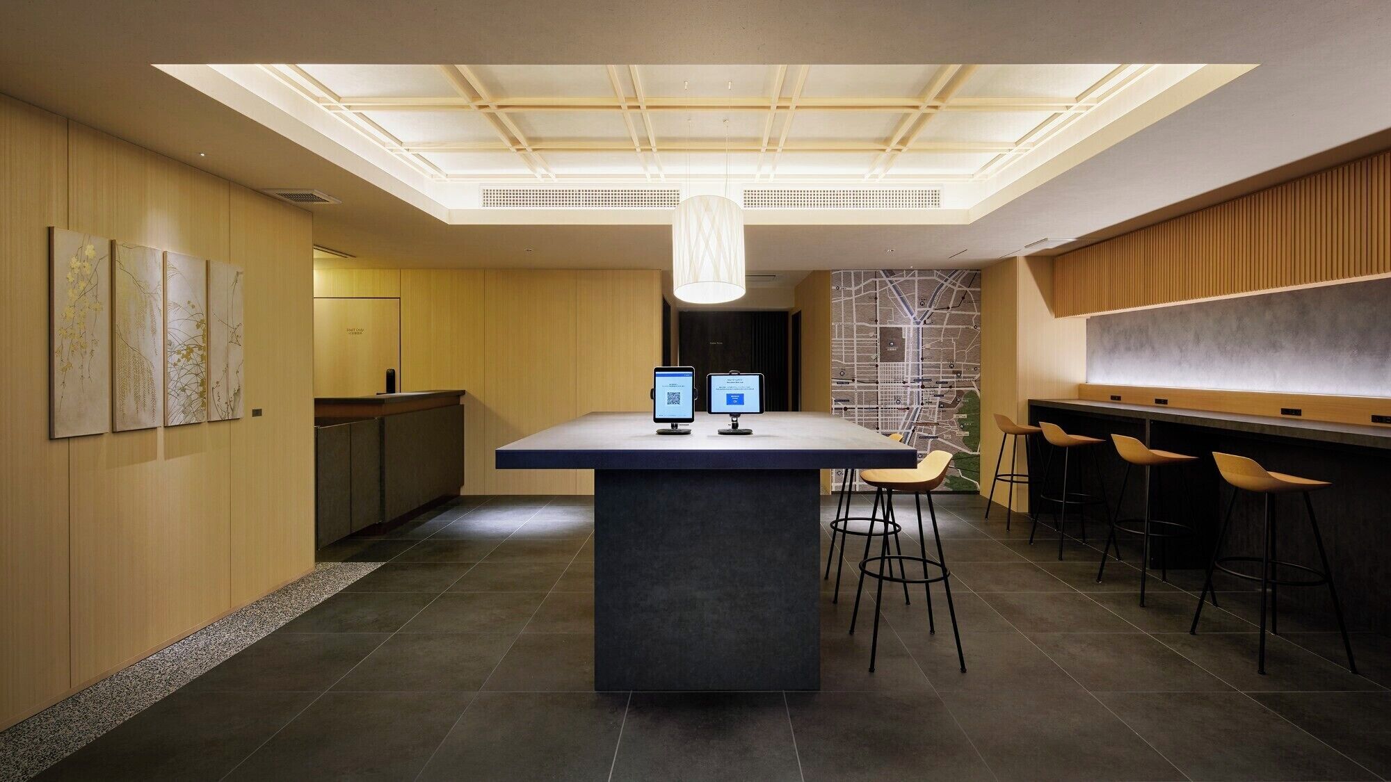 Een moderne bar met een centraal eiland, twee monitoren en barstoelen.
