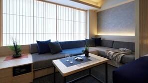 Ein modernes Wohnzimmer mit einer Couch, einem Couchtisch und einem kleinen Schreibtisch mit einer Pflanze.