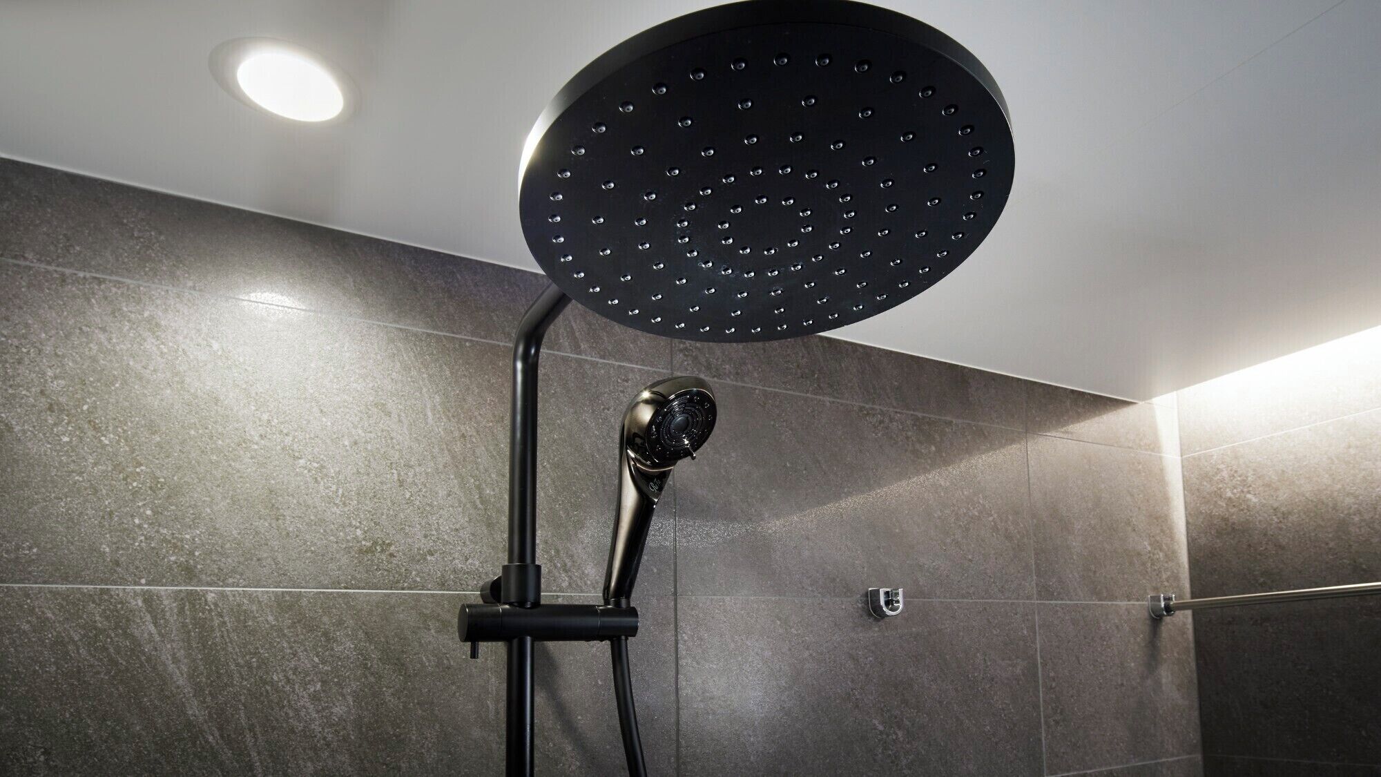 A modern shower with a circular head and a handheld attachment.