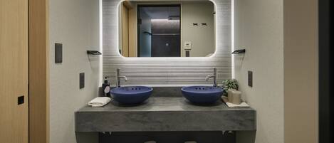 A modern bathroom with two sinks, a large mirror, and a towel rack.
