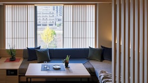 Ett rum med en soffa placerad framför en skjutbar shoji-skärm, ett litet bord med en växt och utsikt över ett bostadsområde.
