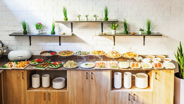 A buffet setup with various food items and a potted plant. - Solief Hotel (Tashkent)