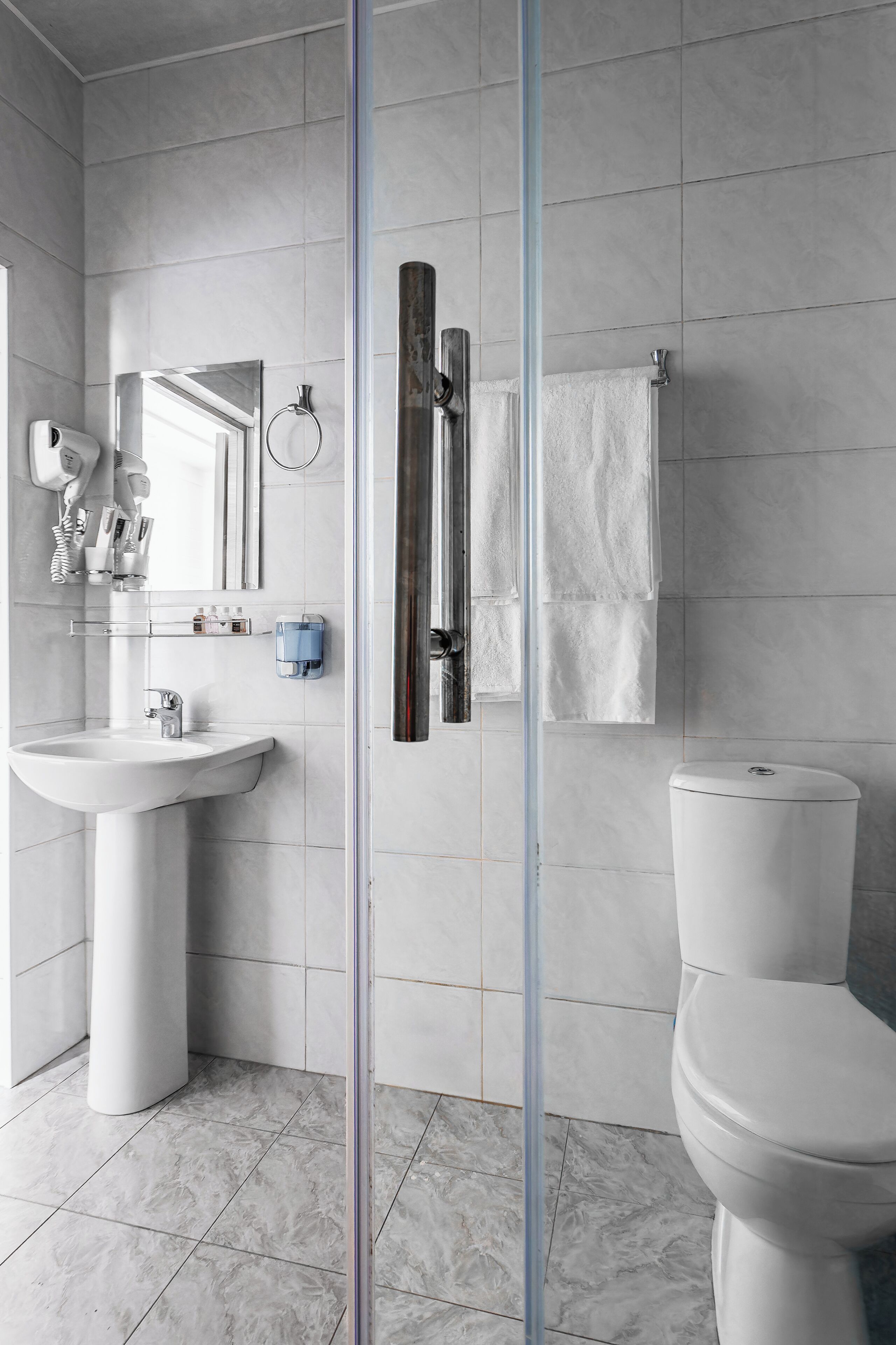 A modern bathroom with a white sink, mirror, and toilet.