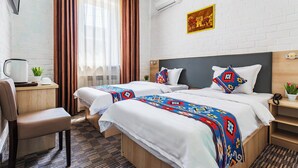 A hotel room with two beds, a desk, a chair, and a small table with a plant. - Solief Hotel (Tashkent)