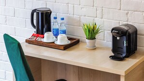 A wooden table with a coffee maker, two water bottles, a tray with coffee cups, a potted plant, and a green chair. - Solief Hotel (Tashkent)