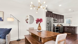 A modern kitchen with dark cabinets, stainless steel appliances, and a wooden dining table with benches.