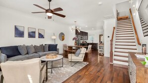 A modern living room with a sofa, coffee table, and chairs. There is a staircase leading to another level.