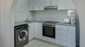 A compact kitchen with a built-in washer, oven, and microwave. - Phaedrus Living: Golden Seaview Residence (Paphos)