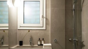 Un baño moderno con cabina de ducha de vidrio, tocador con espejo y un taburete pequeño.