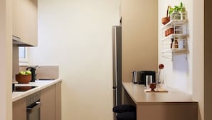 Una cocina compacta con horno integrado, un refrigerador y una pequeña isla con taburetes.