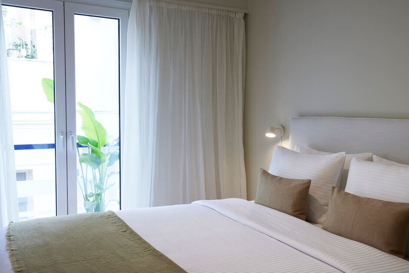 Ein Hotelzimmer mit einem Bett, einem großen Fenster mit Vorhängen und Blick auf Grünfläche.